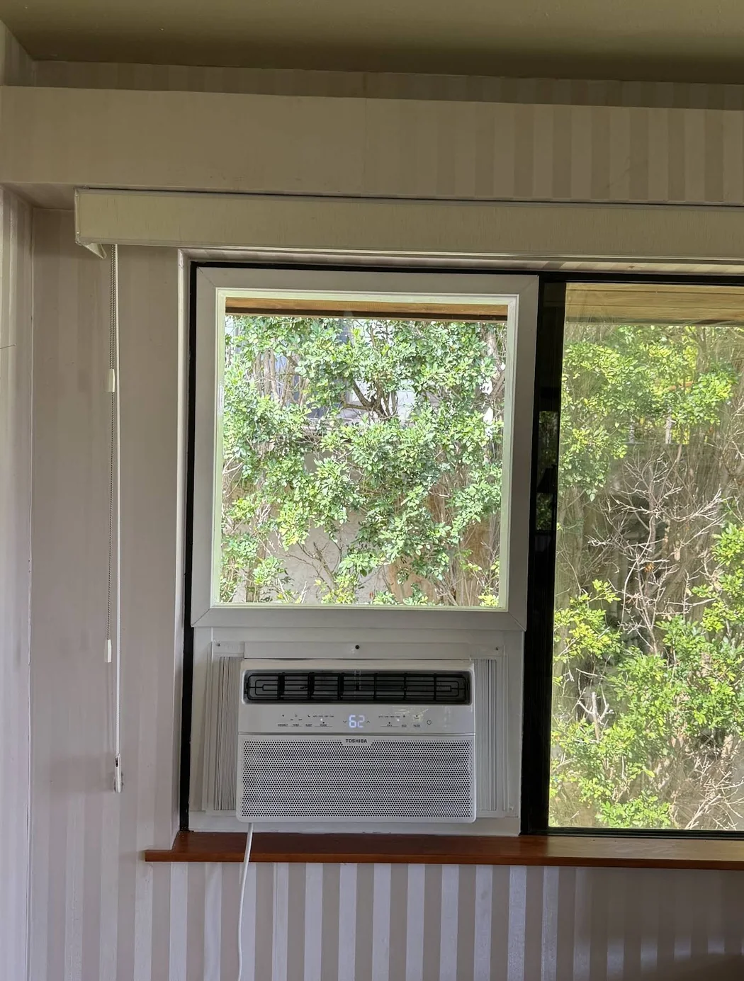 Finished Toshiba window air conditioner installation beneath a custom window panel